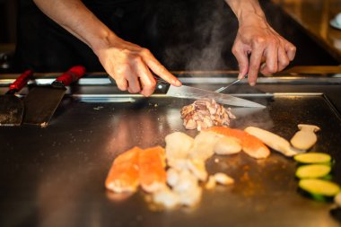 Şefin elleri teppanyaki yerine spatula ile. Sebze pişirmek et ve deniz ürünleri sıcak hibachi ızgara masasında. Geleneksel Japon mutfağı. Teppan gösterisi