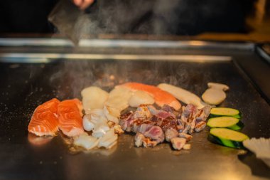 Şefin elleri teppanyaki yerine spatula ile. Sebze pişirmek et ve deniz ürünleri sıcak hibachi ızgara masasında. Geleneksel Japon mutfağı. Teppan gösterisi