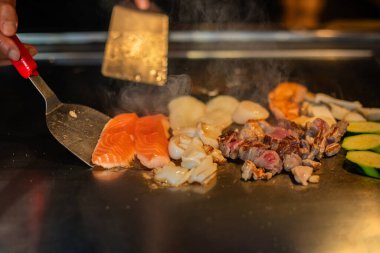 Şefin elleri teppanyaki yerine spatula ile. Sebze pişirmek et ve deniz ürünleri sıcak hibachi ızgara masasında. Geleneksel Japon mutfağı. Teppan gösterisi