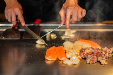 Şefin elleri teppanyaki yerine spatula ile. Sebze pişirmek et ve deniz ürünleri sıcak hibachi ızgara masasında. Geleneksel Japon mutfağı. Teppan gösterisi