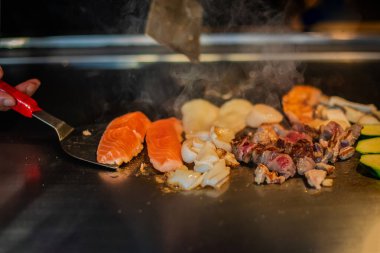 Şefin elleri teppanyaki yerine spatula ile. Sebze pişirmek et ve deniz ürünleri sıcak hibachi ızgara masasında. Geleneksel Japon mutfağı. Teppan gösterisi