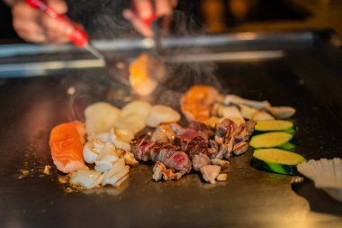 Şefin elleri teppanyaki yerine spatula ile. Sebze pişirmek et ve deniz ürünleri sıcak hibachi ızgara masasında. Geleneksel Japon mutfağı. Teppan gösterisi