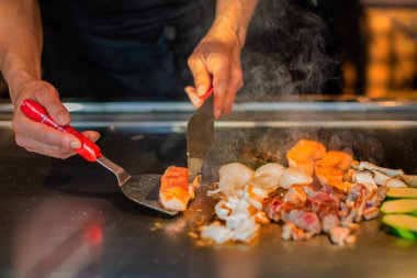Şefin elleri teppanyaki yerine spatula ile. Sebze pişirmek et ve deniz ürünleri sıcak hibachi ızgara masasında. Geleneksel Japon mutfağı. Teppan gösterisi