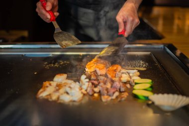 Şefin elleri teppanyaki yerine spatula ile. Sebze pişirmek et ve deniz ürünleri sıcak hibachi ızgara masasında. Geleneksel Japon mutfağı. Teppan gösterisi