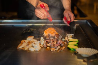 Şefin elleri teppanyaki yerine spatula ile. Sebze pişirmek et ve deniz ürünleri sıcak hibachi ızgara masasında. Geleneksel Japon mutfağı. Teppan gösterisi