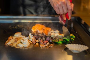 Şefin elleri teppanyaki yerine spatula ile. Sebze pişirmek et ve deniz ürünleri sıcak hibachi ızgara masasında. Geleneksel Japon mutfağı. Teppan gösterisi