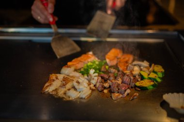 Şefin elleri teppanyaki yerine spatula ile. Sebze pişirmek et ve deniz ürünleri sıcak hibachi ızgara masasında. Geleneksel Japon mutfağı. Teppan gösterisi