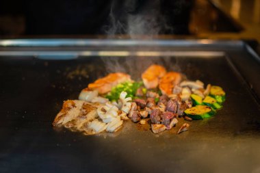 Şefin elleri teppanyaki yerine spatula ile. Sebze pişirmek et ve deniz ürünleri sıcak hibachi ızgara masasında. Geleneksel Japon mutfağı. Teppan gösterisi