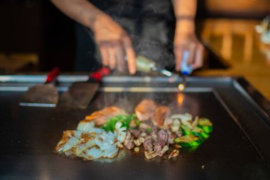 Şefin elleri teppanyaki yerine spatula ile. Sebze pişirmek et ve deniz ürünleri sıcak hibachi ızgara masasında. Geleneksel Japon mutfağı. Teppan gösterisi