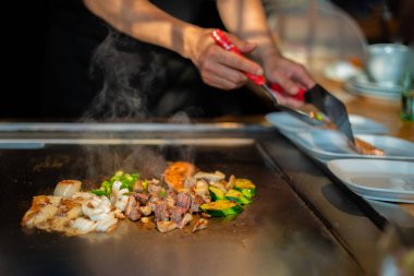 Şefin elleri teppanyaki yerine spatula ile. Sebze pişirmek et ve deniz ürünleri sıcak hibachi ızgara masasında. Geleneksel Japon mutfağı. Teppan gösterisi