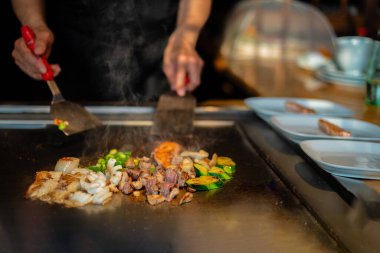 Şefin elleri teppanyaki yerine spatula ile. Sebze pişirmek et ve deniz ürünleri sıcak hibachi ızgara masasında. Geleneksel Japon mutfağı. Teppan gösterisi