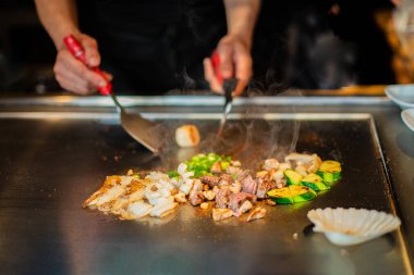 Şefin elleri teppanyaki yerine spatula ile. Sebze pişirmek et ve deniz ürünleri sıcak hibachi ızgara masasında. Geleneksel Japon mutfağı. Teppan gösterisi