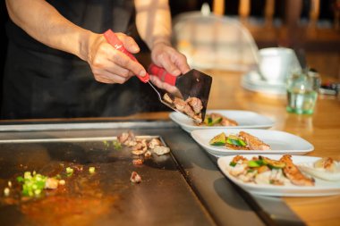 Şefin elleri teppanyaki yerine spatula ile. Sebze pişirmek et ve deniz ürünleri sıcak hibachi ızgara masasında. Geleneksel Japon mutfağı. Teppan gösterisi