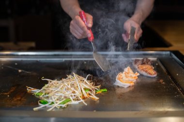 Şefin elleri teppanyaki yerine spatula ile. Sebze pişirmek et ve deniz ürünleri sıcak hibachi ızgara masasında. Geleneksel Japon mutfağı. Teppan gösterisi