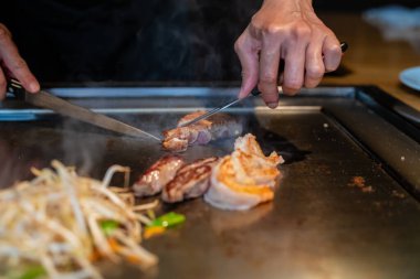 Şefin elleri teppanyaki yerine spatula ile. Sebze pişirmek et ve deniz ürünleri sıcak hibachi ızgara masasında. Geleneksel Japon mutfağı. Teppan gösterisi