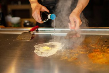 Şefin elleri teppanyaki yerine spatula ile. Sebze pişirmek et ve deniz ürünleri sıcak hibachi ızgara masasında. Geleneksel Japon mutfağı. Teppan gösterisi