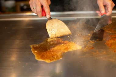 Şefin elleri teppanyaki yerine spatula ile. Sebze pişirmek et ve deniz ürünleri sıcak hibachi ızgara masasında. Geleneksel Japon mutfağı. Teppan gösterisi