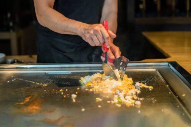 Şefin elleri teppanyaki yerine spatula ile. Sebze pişirmek et ve deniz ürünleri sıcak hibachi ızgara masasında. Geleneksel Japon mutfağı. Teppan gösterisi