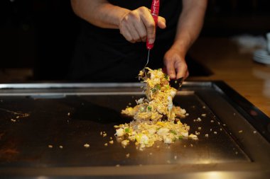 Şefin elleri teppanyaki yerine spatula ile. Sebze pişirmek et ve deniz ürünleri sıcak hibachi ızgara masasında. Geleneksel Japon mutfağı. Teppan gösterisi