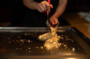 Şefin elleri teppanyaki yerine spatula ile. Sebze pişirmek et ve deniz ürünleri sıcak hibachi ızgara masasında. Geleneksel Japon mutfağı. Teppan gösterisi