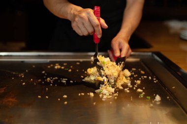 Şefin elleri teppanyaki yerine spatula ile. Sebze pişirmek et ve deniz ürünleri sıcak hibachi ızgara masasında. Geleneksel Japon mutfağı. Teppan gösterisi