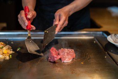Şefin elleri teppanyaki yerine spatula ile. Sebze pişirmek et ve deniz ürünleri sıcak hibachi ızgara masasında. Geleneksel Japon mutfağı. Teppan gösterisi