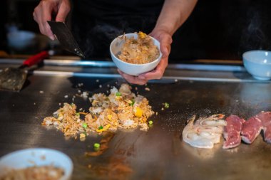 Şefin elleri teppanyaki yerine spatula ile. Sebze pişirmek et ve deniz ürünleri sıcak hibachi ızgara masasında. Geleneksel Japon mutfağı. Teppan gösterisi