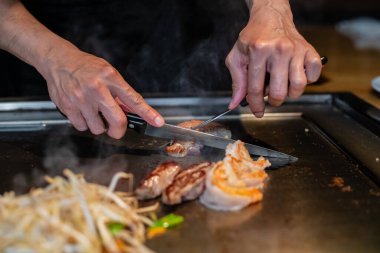 Şefin elleri teppanyaki yerine spatula ile. Sebze pişirmek et ve deniz ürünleri sıcak hibachi ızgara masasında. Geleneksel Japon mutfağı. Teppan gösterisi