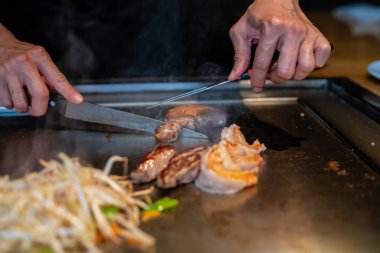 Şefin elleri teppanyaki yerine spatula ile. Sebze pişirmek et ve deniz ürünleri sıcak hibachi ızgara masasında. Geleneksel Japon mutfağı. Teppan gösterisi