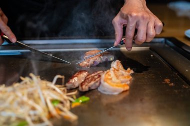 Şefin elleri teppanyaki yerine spatula ile. Sebze pişirmek et ve deniz ürünleri sıcak hibachi ızgara masasında. Geleneksel Japon mutfağı. Teppan gösterisi