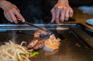 Şefin elleri teppanyaki yerine spatula ile. Sebze pişirmek et ve deniz ürünleri sıcak hibachi ızgara masasında. Geleneksel Japon mutfağı. Teppan gösterisi
