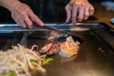Şefin elleri teppanyaki yerine spatula ile. Sebze pişirmek et ve deniz ürünleri sıcak hibachi ızgara masasında. Geleneksel Japon mutfağı. Teppan gösterisi
