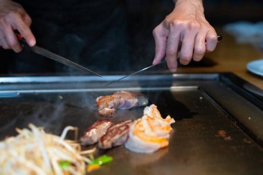 Şefin elleri teppanyaki yerine spatula ile. Sebze pişirmek et ve deniz ürünleri sıcak hibachi ızgara masasında. Geleneksel Japon mutfağı. Teppan gösterisi