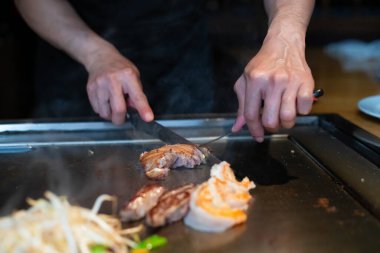Şefin elleri teppanyaki yerine spatula ile. Sebze pişirmek et ve deniz ürünleri sıcak hibachi ızgara masasında. Geleneksel Japon mutfağı. Teppan gösterisi