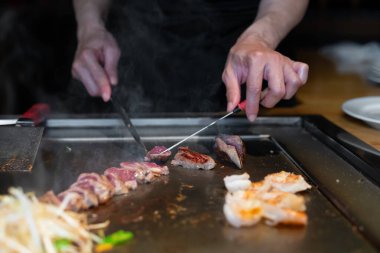 Şefin elleri teppanyaki yerine spatula ile. Sebze pişirmek et ve deniz ürünleri sıcak hibachi ızgara masasında. Geleneksel Japon mutfağı. Teppan gösterisi