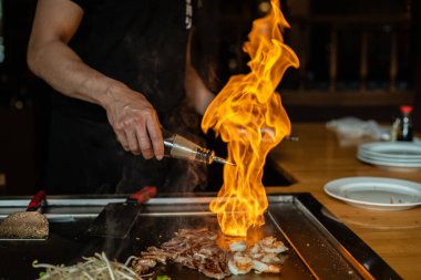Şefin elleri teppanyaki yerine spatula ile. Sebze pişirmek et ve deniz ürünleri sıcak hibachi ızgara masasında. Geleneksel Japon mutfağı. Teppan gösterisi
