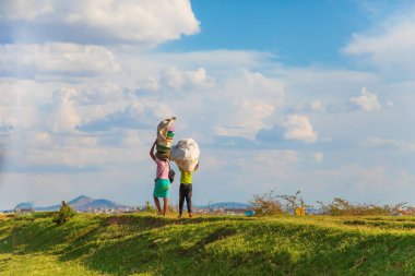 Antananarivo, Talatamaty, Madagaskar. 25 Ekim 2023 Antananarivo Caddesi. Madagaskar 'ın başkenti ve en büyük şehri. İnsanlar toprak seti boyunca arka planda mavi gökyüzüne karşı yürür.