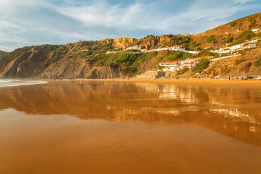 Arrifana, Aljezur, Portekiz. 09 numara. 29 yaşında. 20.20.sörfçüler Portekiz 'de yerler. Güzel körfez ıslak altın kumu ayna gibi, gün batımı. Uzaktaki insanlar ve binalar. Sörf sporu sağlık ve seyahat konsepti