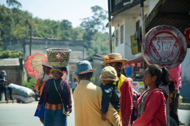 Madagaskar. 25 Ekim 2023 Tipik Madagaskar manzarası. Yol boyunca yürüyen parlak elbiseli insanlar. Kafalarında ağır yük taşıyan kadınlar, sepetler ve çantalar