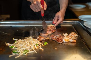 Şefin elleri teppanyaki yerine spatula ile. Sebze pişirmek et ve deniz ürünleri sıcak hibachi ızgara masasında. Geleneksel Japonca. Teppan gösterisi. Dünya mutfağı kavramı