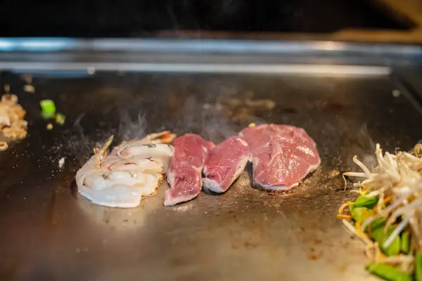 Şefin elleri teppanyaki yerine spatula ile. Sebze pişirmek et ve deniz ürünleri sıcak hibachi ızgara masasında. Geleneksel Japon mutfağı. Teppan gösterisi