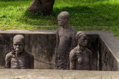 Zanzibar, Tanzanya, Afrika. 26 Mart 2018. Sömürge döneminde kölelerin zor yaşamlarını anma töreni. Kölelerin tutulduğu gerçek çukurlardaki taş heykeller ve demir zincirler.