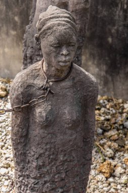 Zanzibar, Tanzanya, Afrika. 26 Mart 2018. Sömürge döneminde kölelerin zor yaşamlarını anma töreni. Kölelerin tutulduğu gerçek çukurlardaki taş heykeller ve demir zincirler.