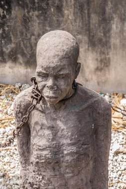 Zanzibar, Tanzanya, Afrika. 26 Mart 2018. Sömürge döneminde kölelerin zor yaşamlarını anma töreni. Kölelerin tutulduğu gerçek çukurlardaki taş heykeller ve demir zincirler.