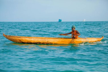 Morondava, Madagaskar. 18 Ekim 2023. Ev yapımı ahşap pirogue teknesindeki kötü niyetli balıkçı ağla balık yakalar. seçici odak, yakın plan