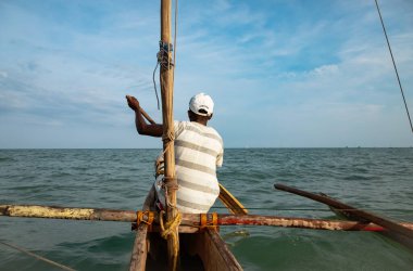 Morondava, Madagaskar. 18 Ekim 2023. Ev yapımı ahşap pirogue teknesindeki kötü niyetli balıkçı ağla balık yakalar. seçici odak, yakın plan