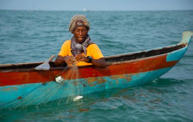 Morondava, Madagaskar. 18 Ekim 2023. Ev yapımı ahşap pirogue teknesindeki kötü niyetli balıkçı ağla balık yakalar. seçici odak, okyanusun yakın görüntüsü