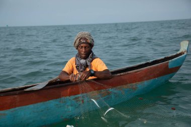 Morondava, Madagaskar. 18 Ekim 2023. Ev yapımı ahşap pirogue teknesindeki kötü niyetli balıkçı ağla balık yakalar. seçici odak, okyanusun yakın görüntüsü