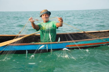 Morondava, Madagaskar. 18 Ekim 2023. Ev yapımı ahşap pirogue teknesindeki kötü niyetli balıkçı ağla balık yakalar. seçici odak, okyanusun yakın görüntüsü