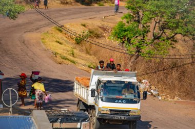Antsirabe, Madagaskar 19 Ekim 2023. Morondava 'dan Antsirabe' ye giden yol Madagaskar 'ın ortasındaki boş otlaklar ve köyden geçiyor. İnşaat işçileri tuğlaların arasında kamyon sürüyor